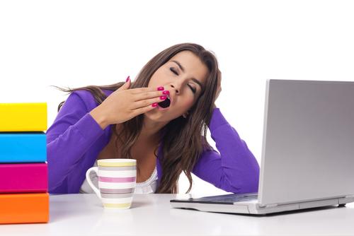 woman-yawning-coffee-books-and-laptop-desk